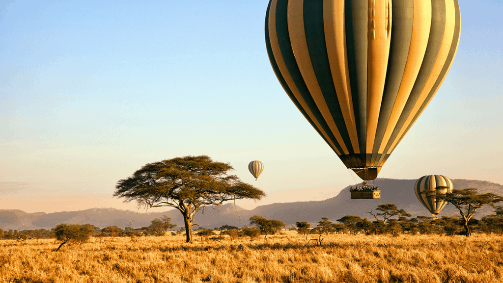Ein Heißluftballon startet seine Fahrt am frühen Morgen in der Serengeti